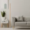 To the left of the gray sofa stands a modern LED ash wood floor lamp.