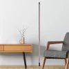 Between the yellow table and gray chair stands a black walnut floor lamp.