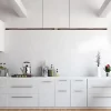 A black walnut chandelier hangs from the kitchen ceiling, with spices and two plants on the white countertop, along with a kettle and a heater.