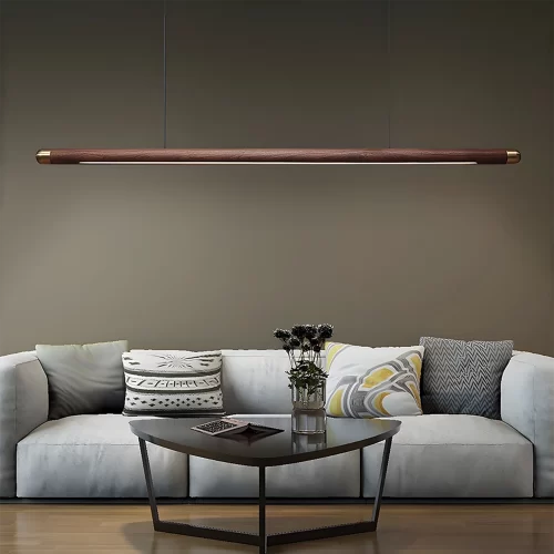 A pendant light hangs from the ceiling in a living room with a light gray fabric sofa and a black table in front of it.