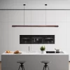 A round rod walnut wood pendant light hangs from the ceiling above the white island in the kitchen.