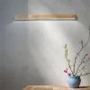 Wood LED Wall Lamp elegantly hangs on the wall above the vase