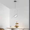 Oval Silver Creative Magpie Bird Rotatable LED Chandelier hangs from the ceiling above the dining table.