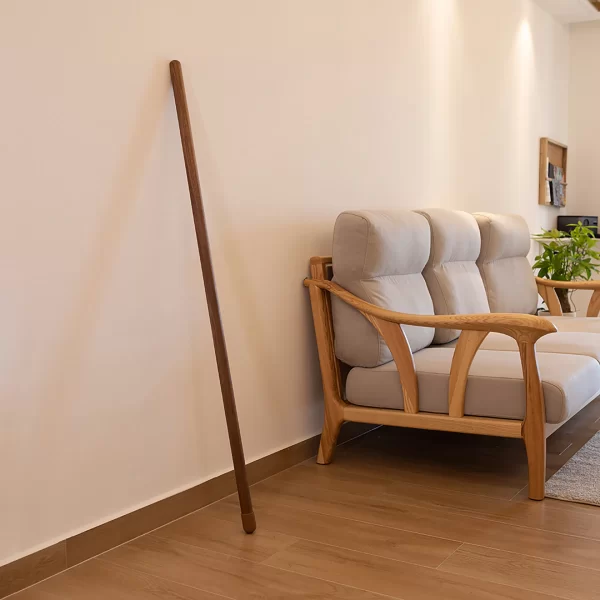 Minimalist black walnut wood LED floor light leans elegantly against the wall